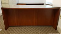 View of the wooden front panel of the Jesper office desk showing its medium brown finish and subtle curved shape.