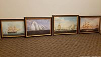 Four sailboat-themed framed artworks resting on floor showing the full set and frame styles