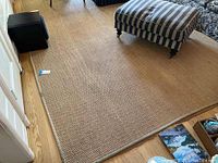 Full view of tan woven sisal rug covering floor area with furniture around it.