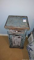 Front view of the antiqued blue wooden end cabinet showing drawer and door closed.