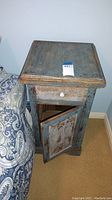 Full view of antiqued wood end table with drawer closed and cabinet door slightly open, showing distressed blue finish.