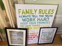 Two framed art prints with motivational text and family rules on a white and black frame.