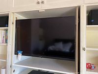 Full front view of the 41 inch Insignia TV mounted on a shelf unit.
