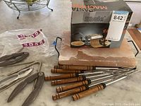 Photo showing pasta maker box, salt block, skewers, and nut cracker on surface.