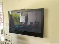 Front view of large black Pioneer flat screen TV mounted on wall, screen is off and reflective.