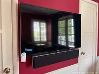Samsung 52-inch flat screen TV mounted on wall with soundbar directly below it. Photo shows front view and size placement.