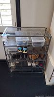 Front view of the metal shoe rack holding several pairs of shoes and storage bins, illustrating the general structure and condition.
