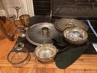 Photo showing various silverplate platters, bowls, candlesticks, and a glass bowl arranged together