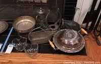 Overview of silver plated items, glass heart-shaped bowls, wire basket, and silver plated teapot on floor