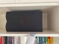 Front view of one black B&W bookshelf speaker on white shelf