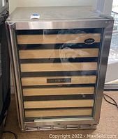 Front view of the wine cellar showing glass door, wooden shelves, and stainless steel frame.