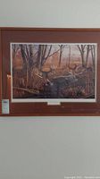Full view of the framed art print showing the painting of three deer running in a forest setting.