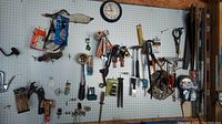Wide view of pegboard with assortment of tools including hand drill, pliers, test equipment, staple gun, and other hardware.