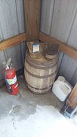 Wooden barrel with block and tackle pulleys on top, next to fire extinguisher and white container.
