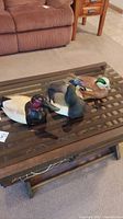 Three wooden duck decoys displayed on a glass table showing scale and condition.