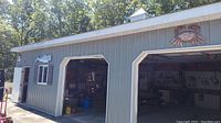 Wide shot showing the garage exterior wall with three outdoor wall hangings: whale on left side wall, crab above garage door, and bird on side wall near window.