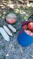 Large orange buoy and three white cylindrical water markers on gravel ground