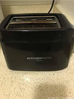 Front view of black 2-slice Kitchen Smith bread toaster with logo visible.