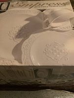 Box of Empress brand charger plates, showing the embossed white plate design and cup, indicating the set contents and brand