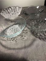 Three glass bowls displayed on a table, showing a variety of shapes and embossed designs.