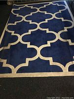 Full view of the blue and white large area rug showing the geometric pattern and the stained surface.
