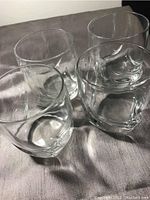 Photo showing four clear cocktail glasses grouped together on a flat surface, highlighting the shape and transparency of the glasses.