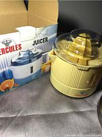 Photo showing the cream-colored Hercules juicer alongside its original packaging box indicating 500 ml capacity.