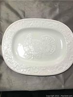 Top view of the white ceramic turkey platter with embossed design in the center and decorative border.