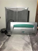 Photo of the Aurora paper shredder with a green top strip and metal mesh basket behind it.