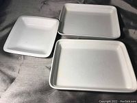 Three white ceramic dishes arranged together: two rectangular and one square. Shows surfaces and shapes clearly.