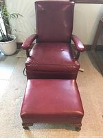 Front view of the red leather armchair and matching ottoman showing the style and condition