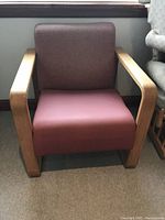Front view of the 1950s armchair showing mauve seat cushion and muted purplish-brown backrest with natural wood frame and armrests.