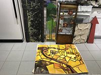 View of the unframed abstract oil painting on canvas laying flat alongside three decorative panels of various sizes and styles, including metal and mirror elements.