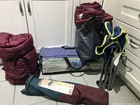 Overview of all items showing red sleeping bags, tent bag, and folding chair
