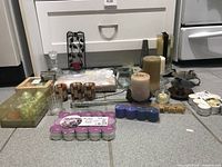 Overview showing assorted candles and candle holders arranged on kitchen floor