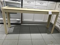 Beige console table front view showing rectangular glass inset in the top.