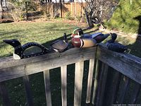 Four wooden duck decoys displayed outdoors on wooden railing in sunlight.