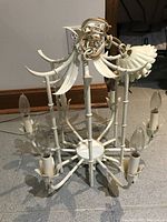 Overall view of chandelier on floor showing six arms, central hub and candelabra sockets