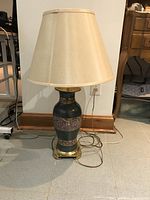 Full view of large ceramic table lamp showing beige fabric lampshade, printed ceramic body with ethnic patterns, and brass base.