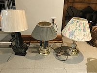 Three table lamps arranged side by side with different bases and shades