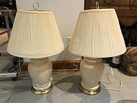 Pair of beige ceramic table lamps side by side showing overall shape, shades, and bases.