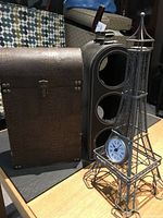 Two items: leather wine bottle holder with three vertical compartments, and mini Eiffel Tower clock on right