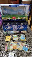Wide shot showing Radiant Eevee premium collection box, two Mewtwo V elite trainer boxes, Mewtwo V card in protective case, pile of Pokemon GO cards and energy cards spread out.