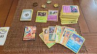 Stack of Pokemon cards, including common and reverse holo, plus 4 coins and some energy cards.