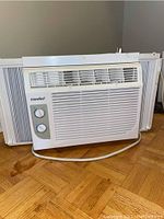 Full view of the Comfee window air conditioning unit showing front grill, side extension panels, and power cord.