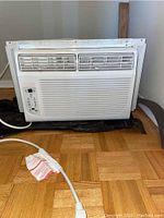 Front view of the white window air conditioner unit showing vents and electronic controls.