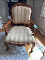Front view of Klaussner International wood arm chair showing carved details and striped upholstery.