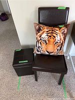 Brown ottoman next to chair with lid removed showing grid tray surface and tiger face pillow on chair