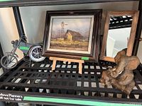 View of the full lot items including motorcycle clock, barn print, mirror, and elephant figurine displayed on a black metal shelf