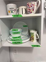Photo displaying five assorted mugs on top shelf